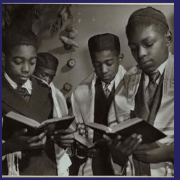 A black and white photo of four boys holding a hymnal in Jewish Harlem one of the many Jewish Neighborhoods in Manhattan.